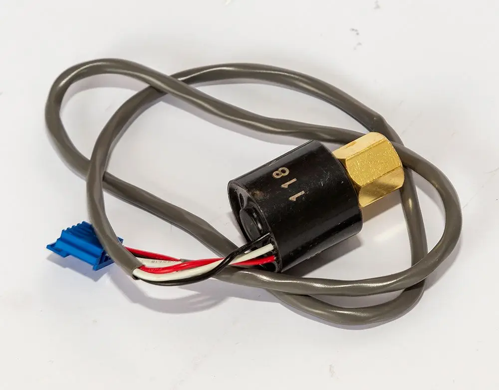 Drucksensor von Daikin mit einem schwarzen Gehäuse und einer goldfarbenen Metallfassung, verbunden mit grauen und roten Leitungen sowie einem blauen Anschluss.